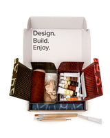 Open craft kit with tools and materials on a white background
